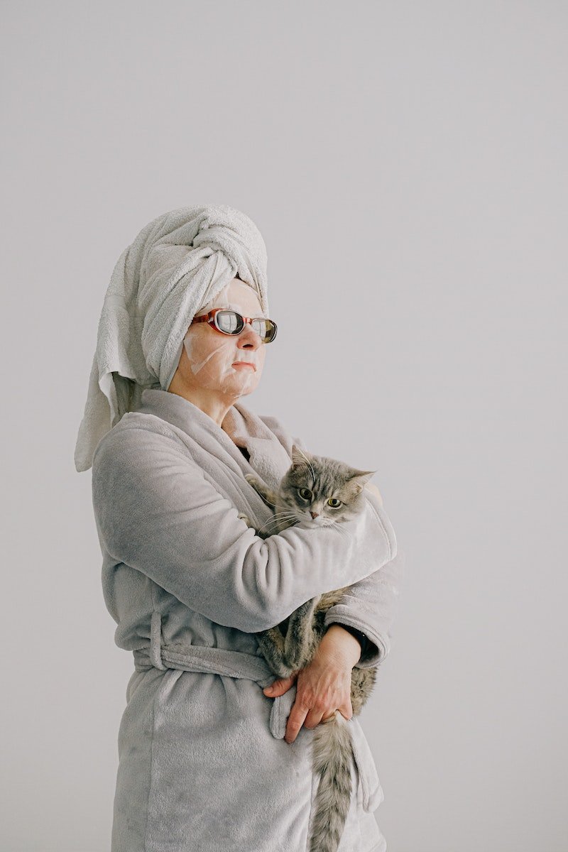 Woman after bath standing with cat in arms