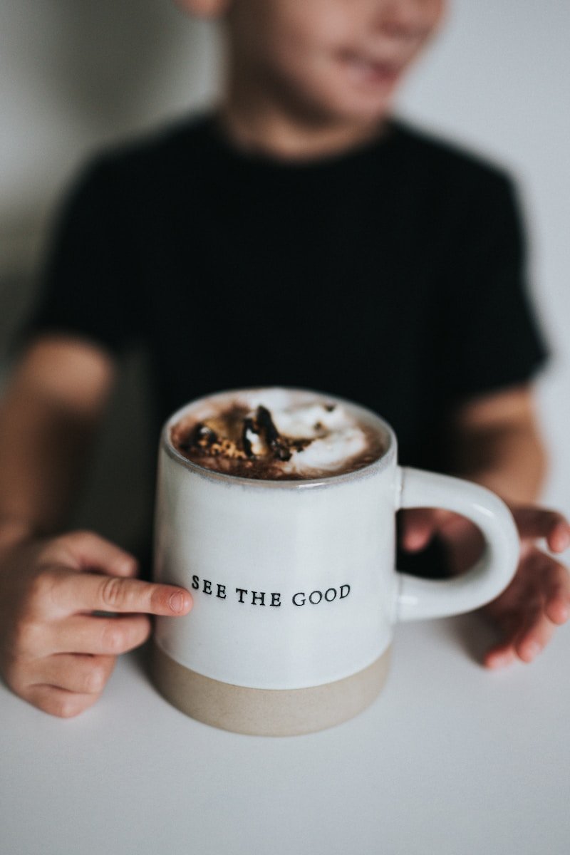 person holding white ceramic mug with coffee