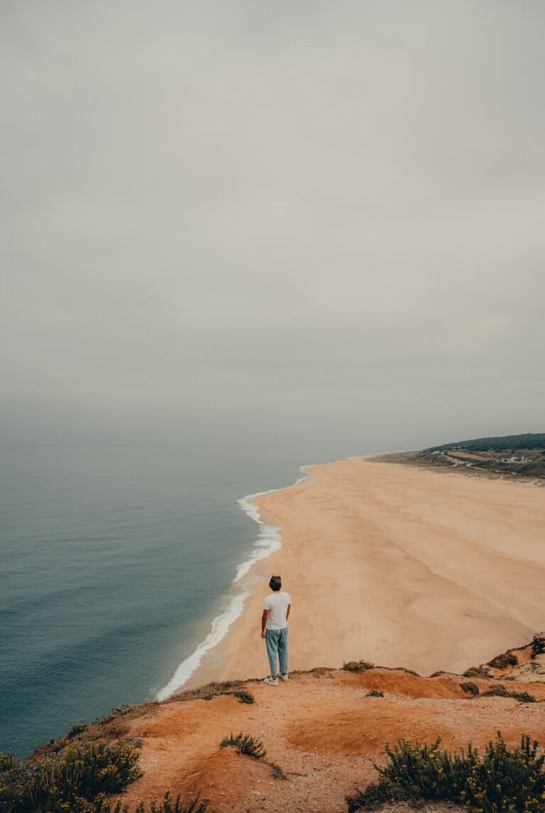 a man standing on top of a sandy beach next to the ocean