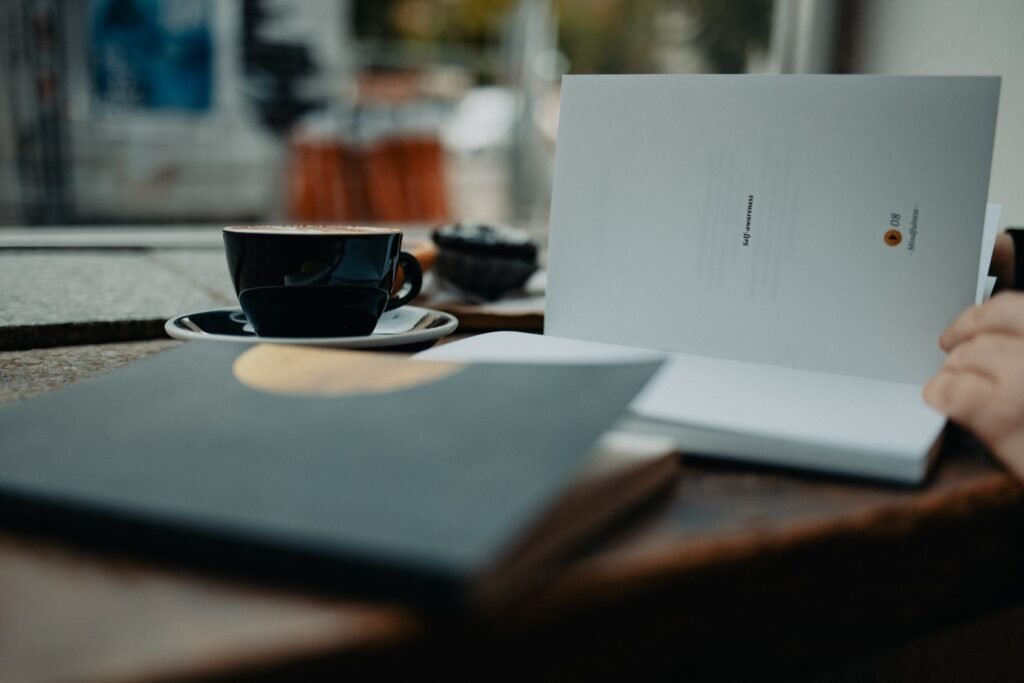 a person sitting at a table with a laptop and a cup of coffee